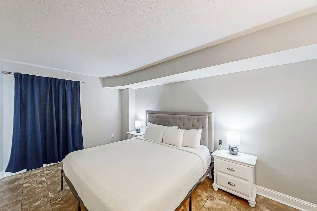 Un dormitorio con cama, mesitas de noche y una lámpara.
