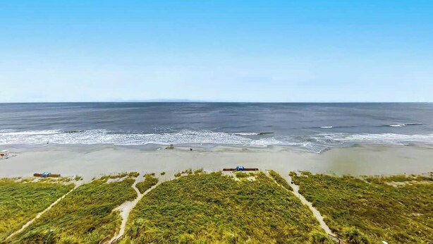 A coastal landscape with a beach, a clear sky, and a path leading to a structure. - Bay Watch Resort 0919 (North Myrtle Beach)