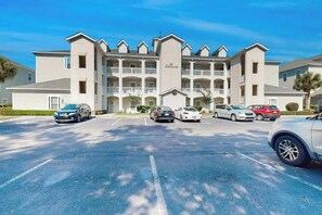 A multi-story hotel with a central entrance and a parking lot with several cars. - 1009 World Tour Unit 306 (Myrtle Beach)