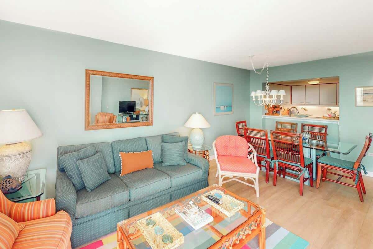 A living room with a sofa, a coffee table, and a dining area with chairs and a table.
