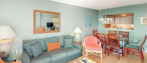 A living room with a sofa, a coffee table, and a dining area with chairs and a table.