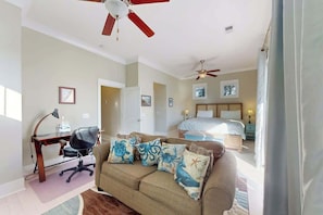 A bedroom with a bed, bedside tables, a desk with a chair, and a ceiling fan. - Seas the Day Retreat (Myrtle Beach)