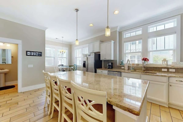 A spacious kitchen with a large island, white cabinetry, and pendant lighting. - Seas the Day Retreat (Myrtle Beach)