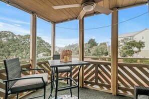 A covered outdoor seating area with a table and chairs, a ceiling fan, and a view of the surrounding neighborhood. - Waipani Unit D-12 Condo (North Myrtle Beach)