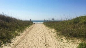 A sandy beach path leading to the ocean, flanked by grassy dunes. - Waipani Unit D-12 Condo (North Myrtle Beach)
