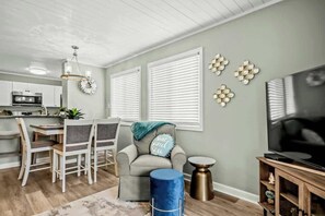 A living room with a dining area, a television, and a kitchen in the background. - Waipani Unit D-12 Condo (North Myrtle Beach)