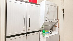 A laundry area with a washing machine and two cabinets. - Waipani Unit D-10 Condo (North Myrtle Beach)