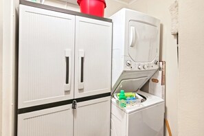A laundry area with a washing machine and two cabinets. - Waipani Unit D-10 Condo (North Myrtle Beach)
