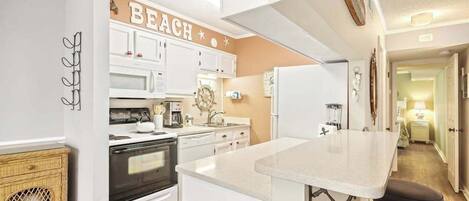A kitchen with white cabinets, a central island, and a 'BEACH' sign.