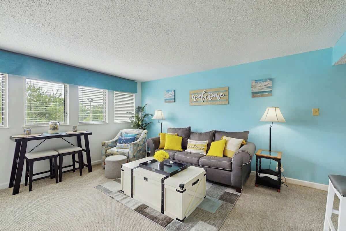 A living room with a sofa, coffee table, and a desk with chairs.