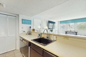 Una cocina con lavavajillas, pileta y un cartel que dice 'Beach Rules'.