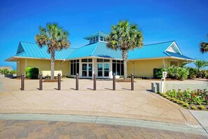 A building with a blue roof, a covered entrance, and palm trees. - Seaside Sanctuary at Litchfield by the Sea (Pawleys Island)