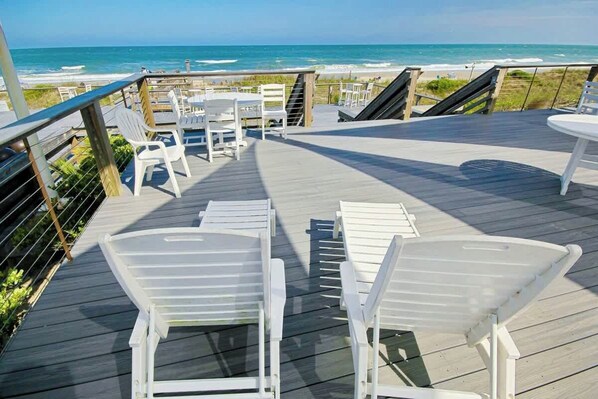 A wooden deck with white chairs and tables overlooking the ocean. - Seaside Sanctuary at Litchfield by the Sea (Pawleys Island)