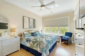 A bedroom with a bed, a chair, a dresser, a ceiling fan, and a window with blinds. - Seaside Sanctuary at Litchfield by the Sea (Pawleys Island)