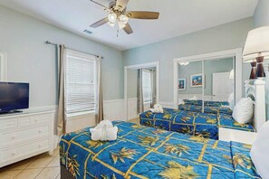 Ein Hotelzimmer mit einem Bett, einem Fernseher, einem Deckenventilator und einem Fenster mit Jalousien.