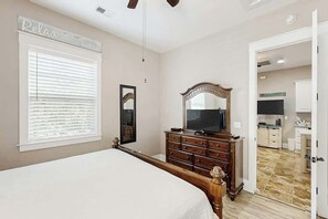 A bedroom with a bed, a dresser, a television, and a mirror. - North Beach Villas 201 (North Myrtle Beach)