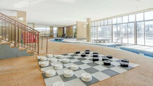 Ett rymligt inomhusområde med en pool, ett schackrutigt spel på golvet och en trappa.