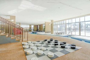 Ein geräumiger Innenbereich mit Schwimmbecken, einem Schachbrettspiel und einer Treppe.