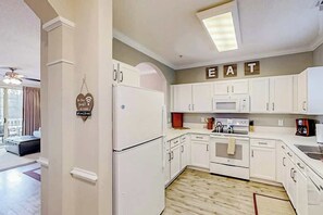 A modern kitchen with white cabinetry, a microwave, an oven, and a refrigerator. - Barefoot Landing Beach and Golf  Resort Villa (North Myrtle Beach)