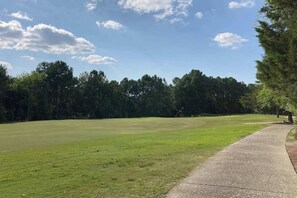 A grassy field with a concrete path curving to the right. - Barefoot Landing Beach and Golf  Resort Villa (North Myrtle Beach)