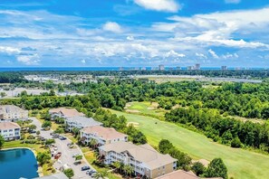 A residential area with houses, a golf course, and a distant city skyline.