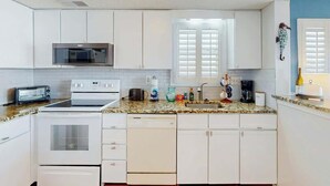 A compact kitchen with white cabinets, a microwave, a stove, a dishwasher, and a sink. - Paradise Palms Retreat (Murrells Inlet)