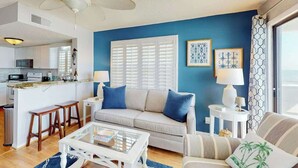 A living room with a sofa, coffee table, and a view of the kitchen. - Paradise Palms Retreat (Murrells Inlet)