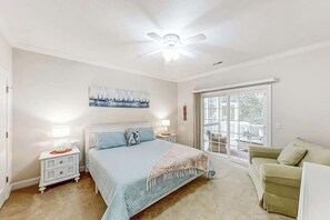 A bedroom with a bed, nightstands, a ceiling fan, a window, and a sliding glass door. - A Shore Pleasure Retreat (North Myrtle Beach)