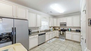 A kitchen with white cabinets, a stainless steel refrigerator, a microwave, and a dishwasher. - A Shore Pleasure Retreat (North Myrtle Beach)