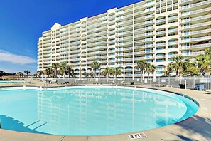 A large hotel with multiple balconies, a swimming pool, and palm trees. - Catalina Cove Retreat (North Myrtle Beach)