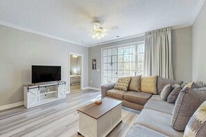 A living room with a television, sofa, and a coffee table. - Catalina Cove Retreat (North Myrtle Beach)