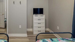 Une chambre à coucher avec un lit, une commode et un téléviseur posé sur le dessus.