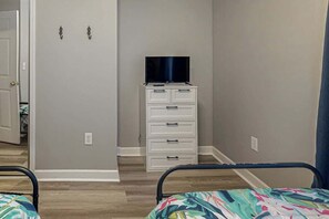 Ein Schlafzimmer mit einem Bett, einem Schminktisch und einem Fernseher darauf.