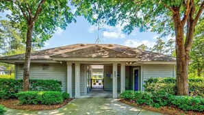 A two-story building with a covered entrance, columns, and a gravel driveway. - Tidewater Dream Retreat (North Myrtle Beach)