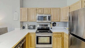 A kitchen with wooden cabinets, a stainless steel refrigerator, a microwave, a stove, and a dishwasher. - Tidewater Dream Retreat (North Myrtle Beach)