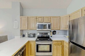 A kitchen with wooden cabinets, a stainless steel refrigerator, a microwave, a stove, and a dishwasher. - Tidewater Dream Retreat (North Myrtle Beach)