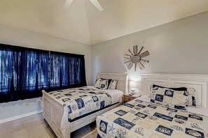A bedroom with two beds, a large window with curtains, a wall clock, and a bedside table with a lamp. - Tidewater Dream Retreat (North Myrtle Beach)