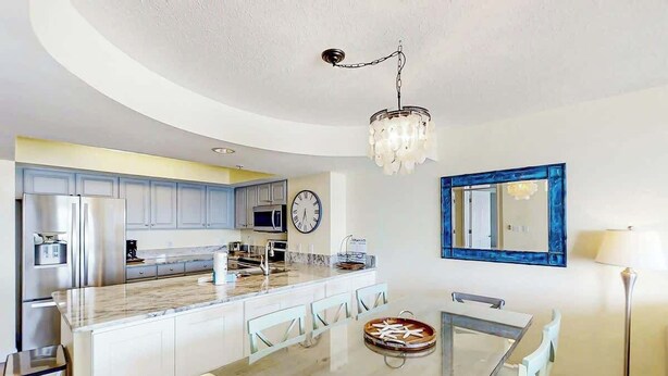 Cozinha moderna com ilha central, eletrodomésticos de aço inoxidável e um lustre.