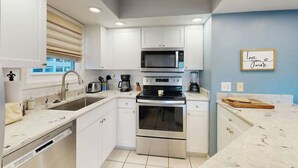 Een moderne keuken met witte kastjes, roestvrijstalen apparatuur en een blauwe accentmuur.