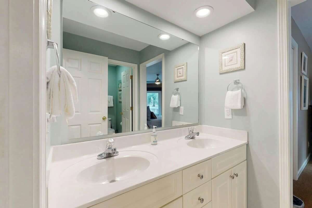 A bathroom with a double sink vanity, a large mirror, and a towel rack.