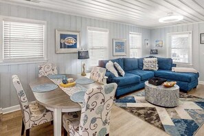 Une pièce avec un canapé bleu, une table à manger avec des chaises et un tapis à motifs.