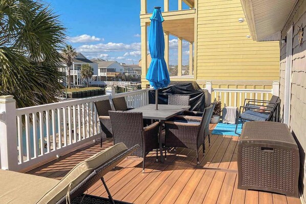 Eine Terrassenausstattung mit Tisch und Stühlen, einem blauen Sonnenschirm und Blick auf den Hafen.