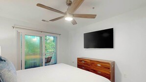 A bedroom with a bed, a wooden dresser, a ceiling fan, and a TV mounted on the wall. - The Fairways Unit 19D (Myrtle Beach)