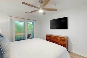A bedroom with a bed, a wooden dresser, a ceiling fan, and a TV mounted on the wall. - The Fairways Unit 19D (Myrtle Beach)