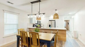A modern kitchen with a central island, wooden chairs, and pendant lighting. - The Fairways Unit 19D (Myrtle Beach)