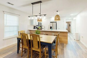 A modern kitchen with a central island, wooden chairs, and pendant lighting. - The Fairways Unit 19D (Myrtle Beach)