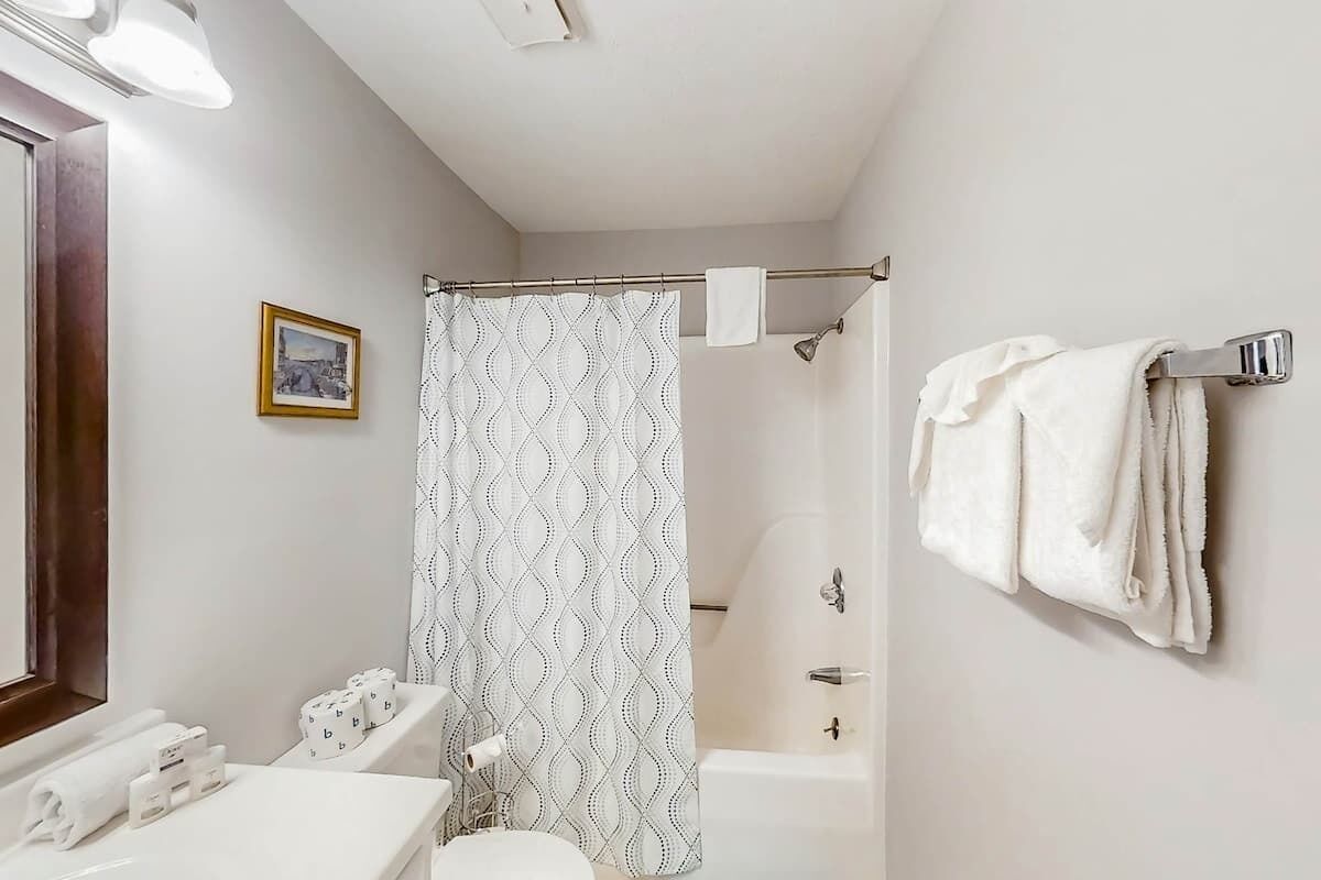 A bathroom with a shower curtain, a toilet, a sink, and a towel rack.