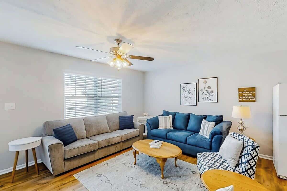 A living room with two sofas, a coffee table, and a ceiling fan.