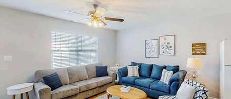 Ein Wohnzimmer mit zwei Sofas, einem Couchtisch und einem Deckenventilator.
