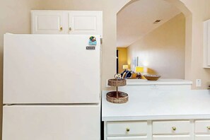 Eine Küche mit einem weißen Kühlschrank, einer weißen Arbeitsplatte und einem weißen Schrank.